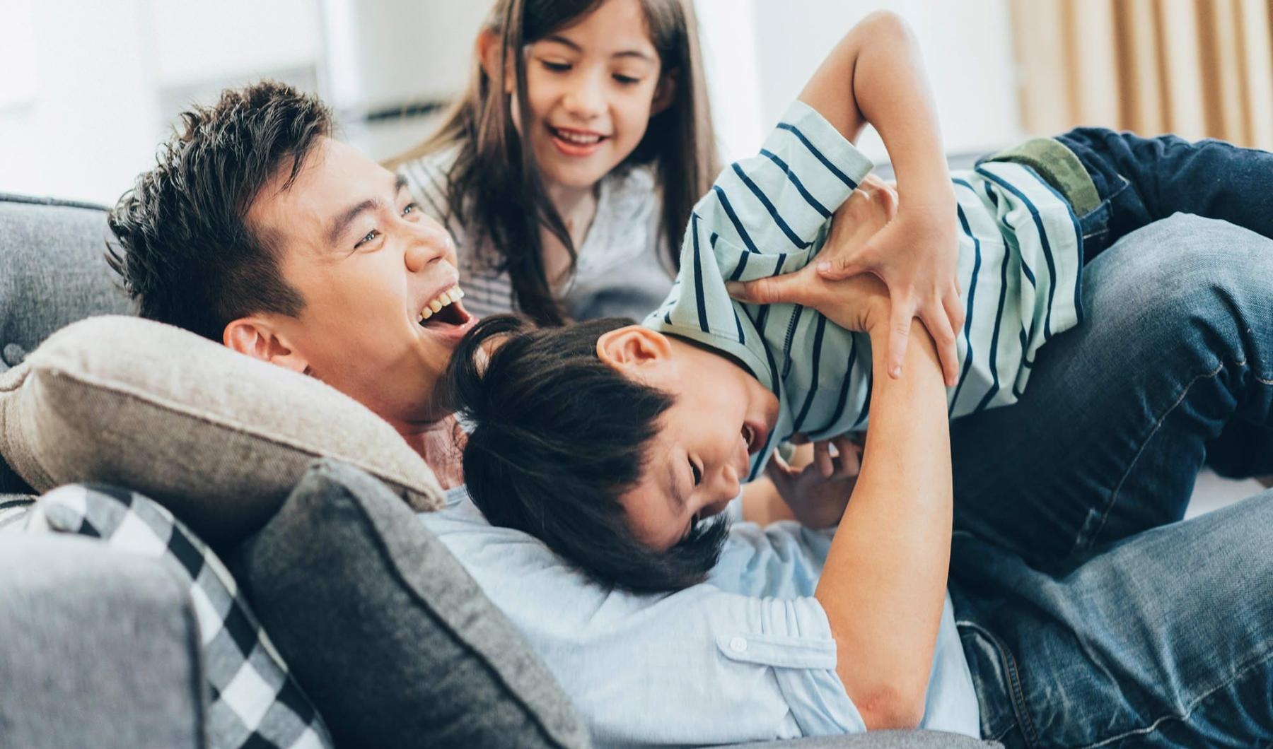 A perfect fit for the whole family father plays on a couch with his young children